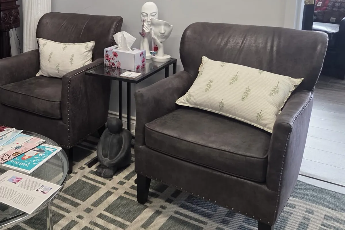 Quiet waiting area with two upholstered armchairs and a small side table at the Mississauga office